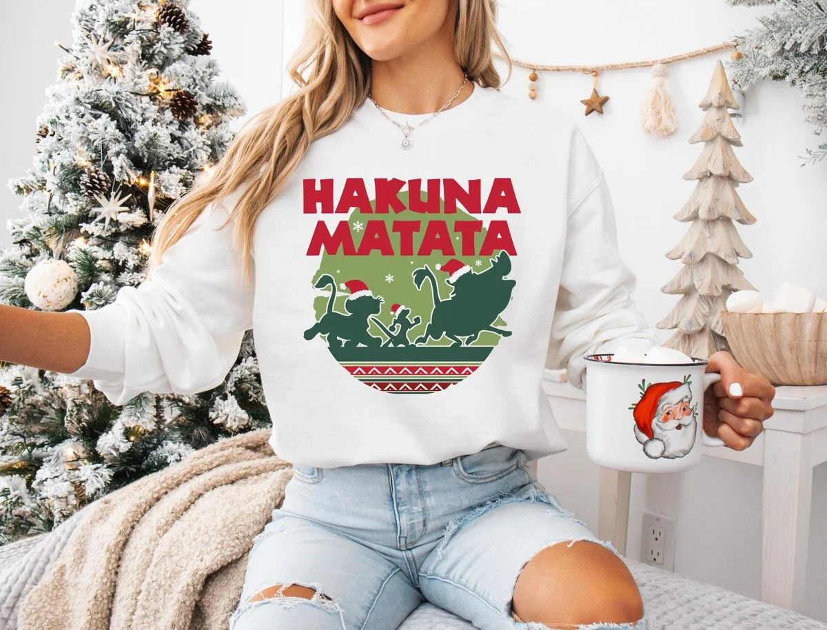 Lion King Hakuna Matata Christmas Sweatshirt with Nordic Art 5 Woman sitting near Christmas tree wearing white lion king holiday sweater crewneck fleece