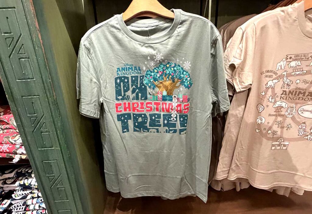 Christmas at Animal Kingdom Secrets Every Traveler Needs for 2027 20 The gray Animal Kingdom Oh Christmas Tree holiday graphic t-shirt on a hanger inside Riverside Depot