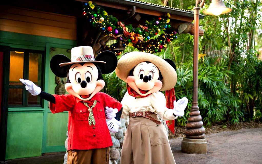 Christmas at Animal Kingdom Secrets Every Traveler Needs for 2027 18 Mickey Mouse in a red safari shirt and Minnie Mouse in a holiday dress and hat posing together at Adventurers Outpost