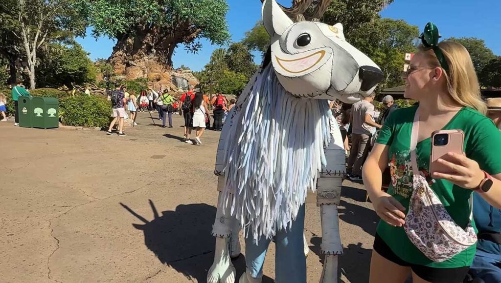 Christmas at Animal Kingdom Secrets Every Traveler Needs for 2027 7 Handcrafted white reindeer puppet greeting a smiling woman wearing Mickey ears in front of the Tree of Life