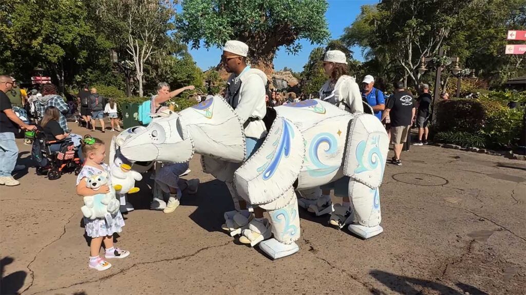 Christmas at Animal Kingdom Secrets Every Traveler Needs for 2027 10 The giant artisan polar bear puppet leaning down to greet a little girl holding a plush polar bear on Discovery Island
