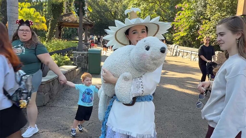 Christmas at Animal Kingdom Secrets Every Traveler Needs for 2027 6 A smiling puppeteer wearing a white petal hat holding a soft white seal puppet next to a young boy and guests on Discovery Island