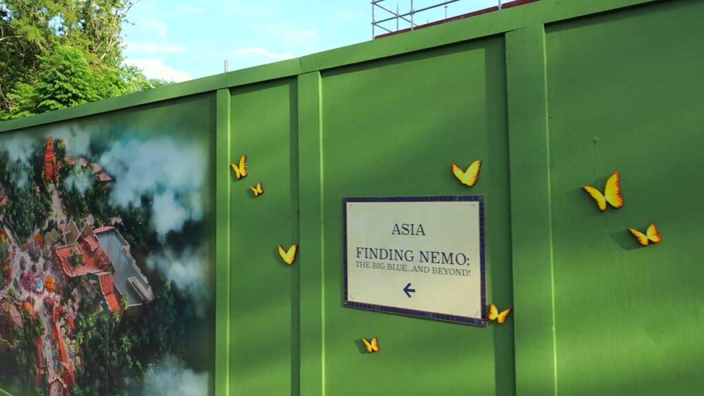 Christmas at Animal Kingdom Secrets Every Traveler Needs for 2027 14 Construction wall sign pointing toward Asia and Finding Nemo The Big Blue and Beyond near the Santa's Holiday Grove walkway